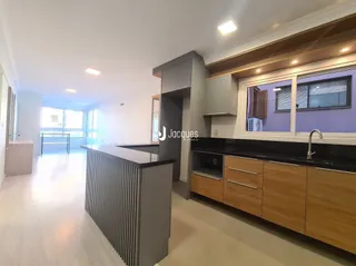 Vista interna de uma sala de estar com cozinha integrada em um imóvel.