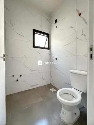 Banheiro com paredes brancas e piso cinza.