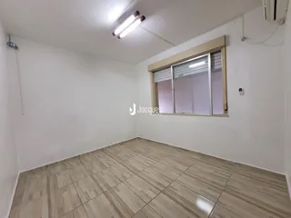 A sala apresenta piso de madeira clara e paredes brancas.