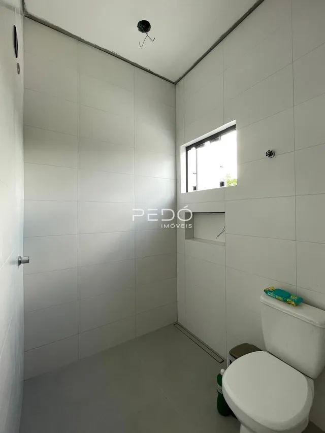Foto interna de um banheiro moderno com revestimento branco.