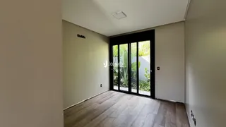 Hall de entrada com piso de madeira e porta de vidro.