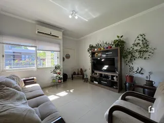 Sala de estar iluminada com sofá e janelas amplas em um imóvel no Brasil.