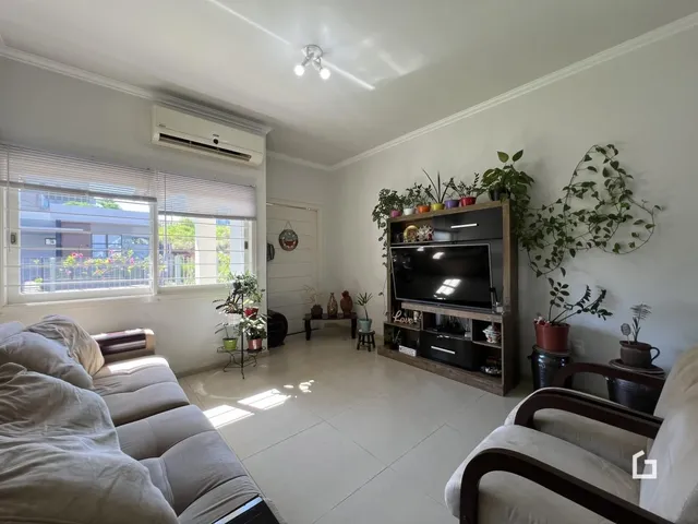 Sala de estar iluminada com sofá e janelas amplas em um imóvel no Brasil.