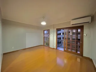 Sala ampla com piso de madeira clara e portas de vidro.