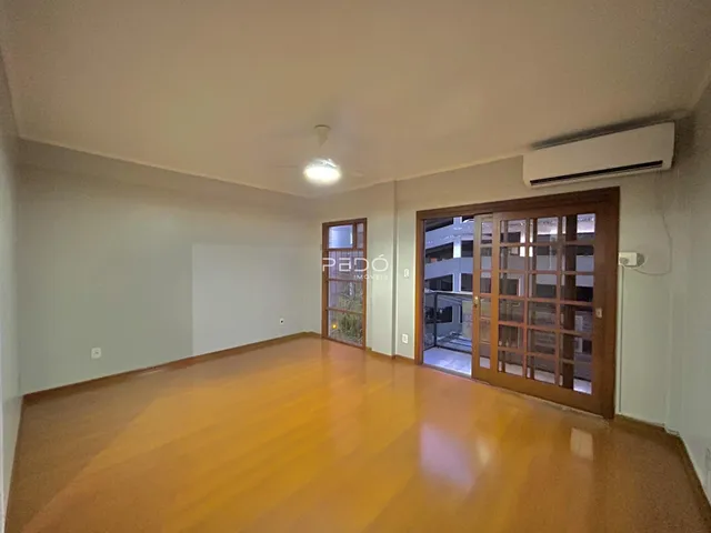 Sala ampla com piso de madeira clara e portas de vidro.
