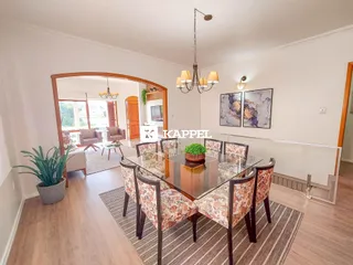 Uma sala de jantar com mesa de vidro e cadeiras decorativas em um ambiente claro.
