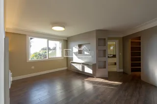 Sala de estar com piso de madeira e grande janela.