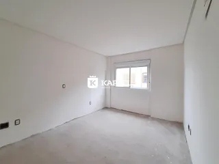 Foto de um cômodo interno vazio com paredes brancas e piso cru.