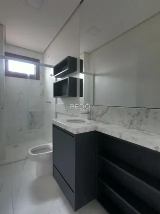 Banheiro moderno com revestimento em mármore e bancada escura.