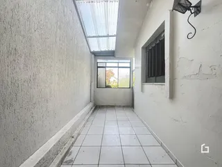 Corredor interno com piso de cerâmica e teto de claraboia.