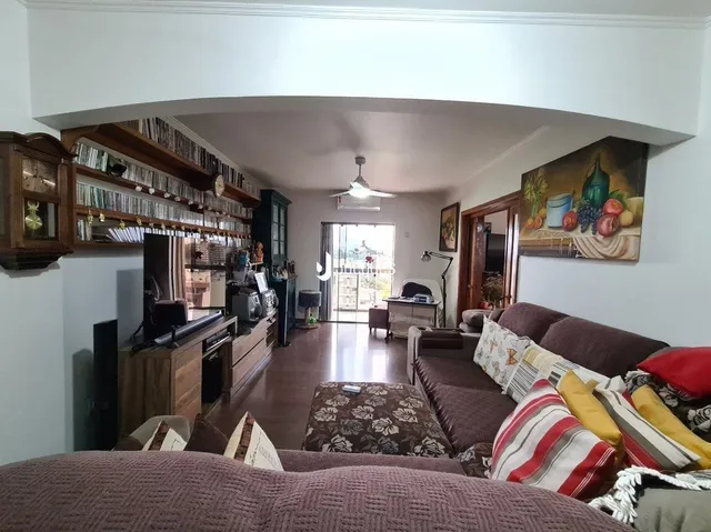 A sala de estar exibe estantes de madeira e um corredor interno.