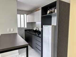 Vista da cozinha com armários brancos e piso de mármore claro.