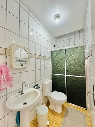 Foto interna de um banheiro com revestimento cerâmico branco.