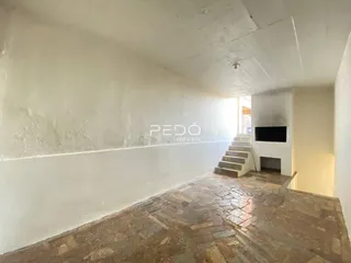 Corredor com piso de pedra e escadaria em uma residência.