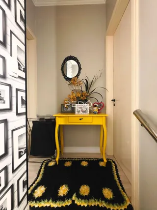 Hall de entrada com um aparador amarelo e tapete escuro.