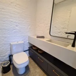 Foto de um banheiro mostrando um vaso sanitário e uma bancada branca.