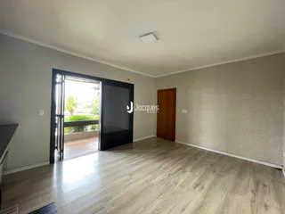 Ambiente interno de uma sala com piso de madeira clara e porta de vidro.
