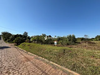 Vista exterior de uma propriedade com estrada e vegetação ao longo de uma rua.