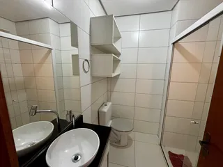 Foto interna de um banheiro com revestimento de azulejos brancos e bancada escura.
