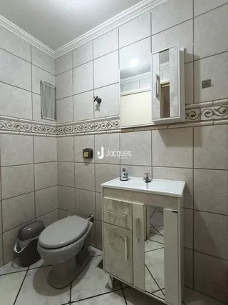 Foto interna de um banheiro com revestimento de azulejos claros.