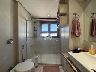 Foto do interior de um banheiro com box de vidro e azulejos.