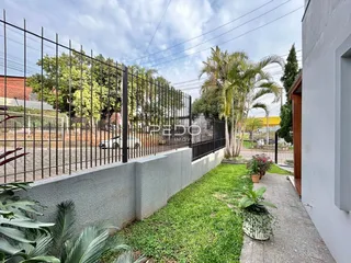 Vista externa de uma propriedade com cerca de ferro e gramado.