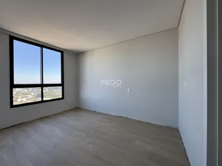 Ambiente interno de uma sala com piso de madeira clara e grande janela.