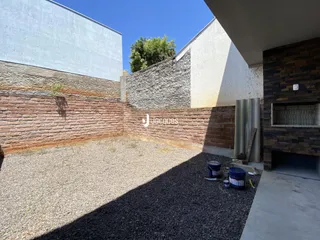 Vista externa de um pátio com solo de cascalho e muros de alvenaria.