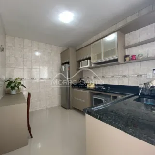 Cozinha com revestimento de azulejos brancos e bancada escura.