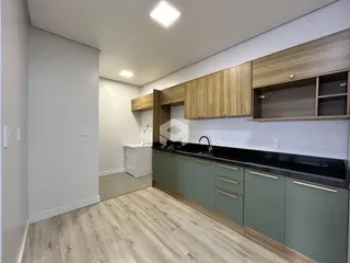 Vista interna de uma cozinha moderna com armários de madeira e bancada escura.