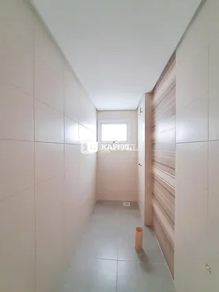 Um corredor interno com paredes brancas e piso de cerâmica.