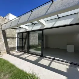 Vista interna de um ambiente com grandes portas de vidro que dão acesso a uma área externa.