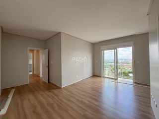 Interior de uma sala com piso de madeira e vista para a paisagem externa.