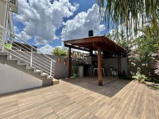 Vista da fachada de uma residência com um pátio coberto e escadaria externa.