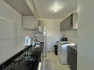 Vista da cozinha moderna com armários brancos e bancadas escuras.