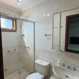 Banheiro com box de vidro e revestimento de azulejos brancos.