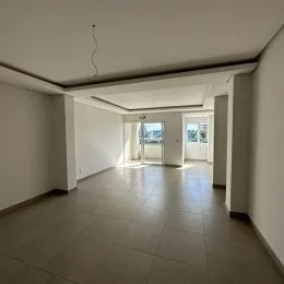 Foto de um corredor interno com piso claro e paredes brancas.