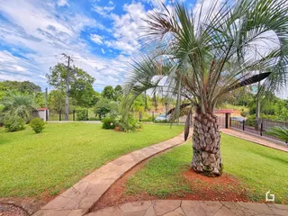 Vista externa de um jardim com gramado e caminho de pedras.