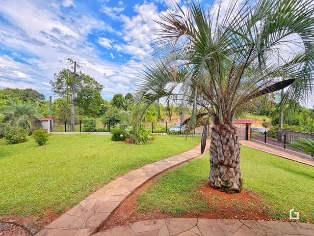 Vista externa de um jardim com gramado e caminho de pedras.