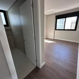 Corredor interno mostrando um ambiente com piso de madeira e paredes brancas.