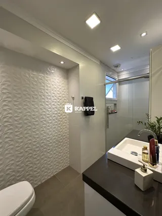Banheiro com revestimento decorativo e bancada escura.