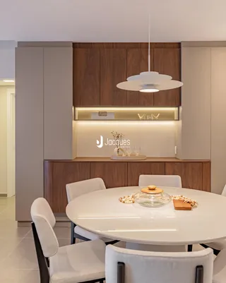 Uma mesa de jantar redonda branca com cadeiras brancas está localizada em um ambiente moderno.
