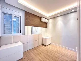 Sala de estar moderna com piso de madeira clara e paredes brancas.