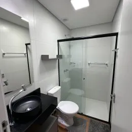 Foto de um banheiro interno com box de vidro e vaso sanitário.