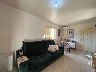 Sala de estar com um sofá verde escuro e piso de cerâmica.