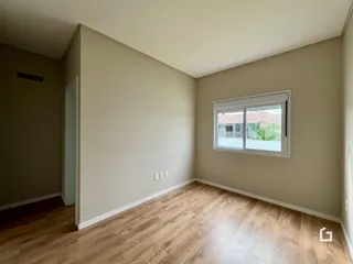 Ambiente interno de uma sala com piso de madeira clara e janela.