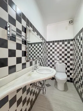 Foto de um banheiro com revestimento de azulejos pretos e brancos.
