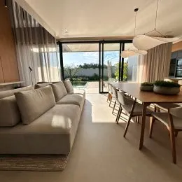 Sala de estar com sofá e portas de vidro que dão acesso ao exterior.