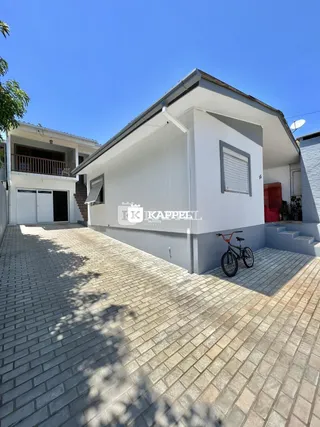 Foto da fachada de uma casa em Lajeado, Brasil, mostrando a entrada e a área externa pavimentada.