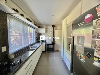 Esta é uma foto de uma cozinha com bancadas escuras e armários brancos.